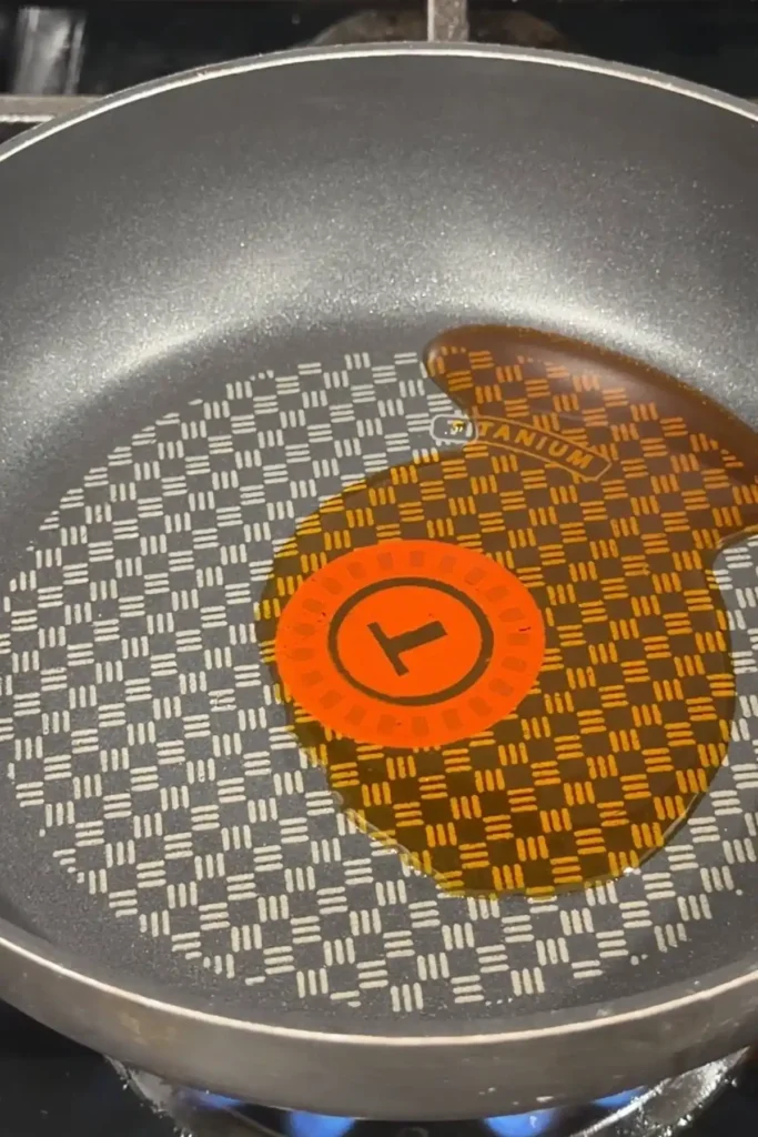 Annatto oil heating in a nonstick pan before making kare kare sauce.