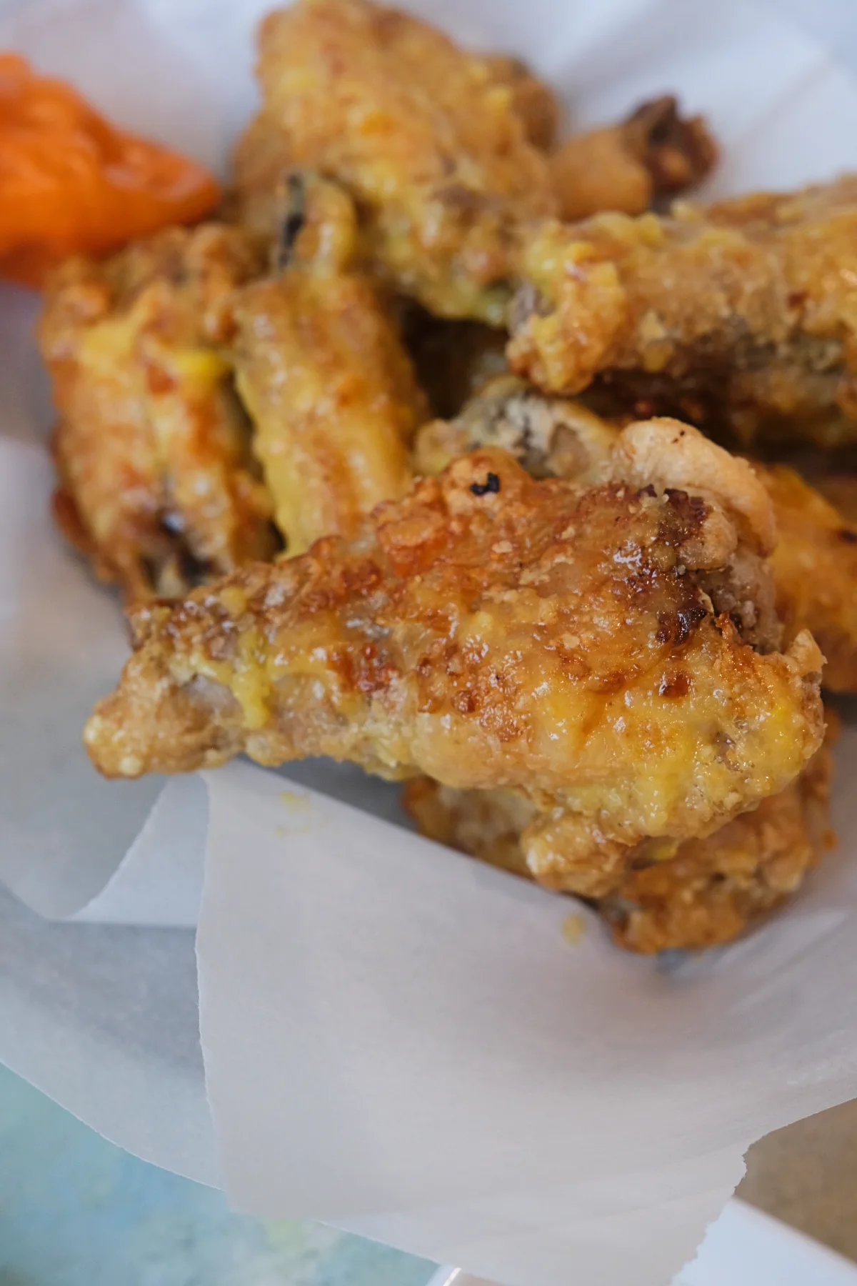 Close-up of a golden crispy mango habanero wing with sticky sauce and crunchy coating.