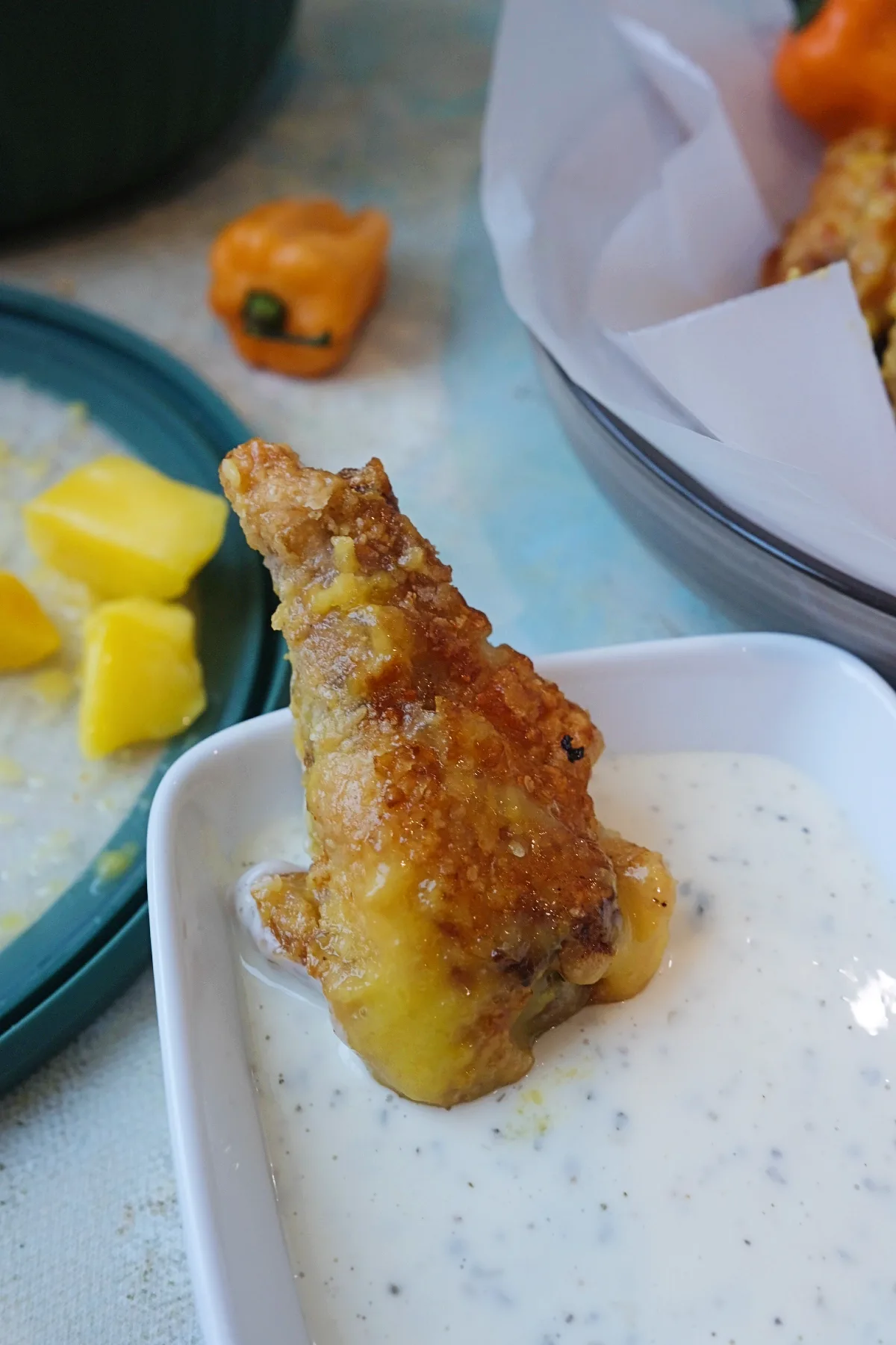Mango habanero chicken wings served in a bowl with ranch dip, mango chunks, and habanero peppers.
