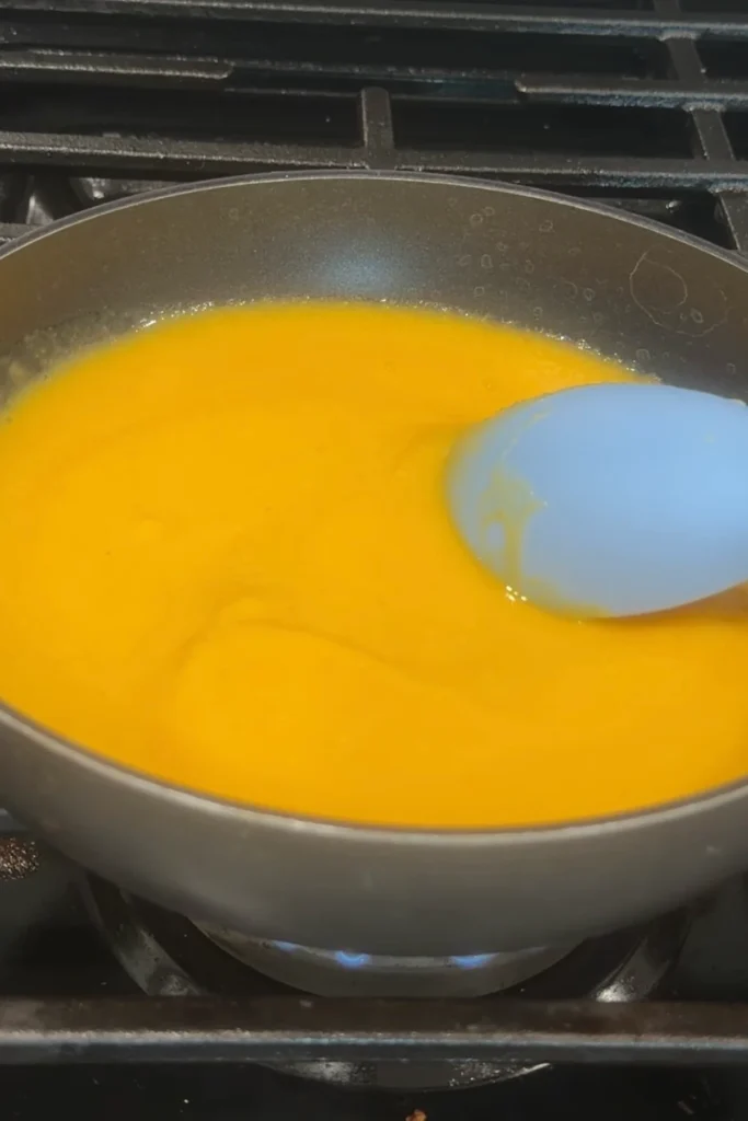 Mango habanero sauce simmering in a saucepan on the stove.
