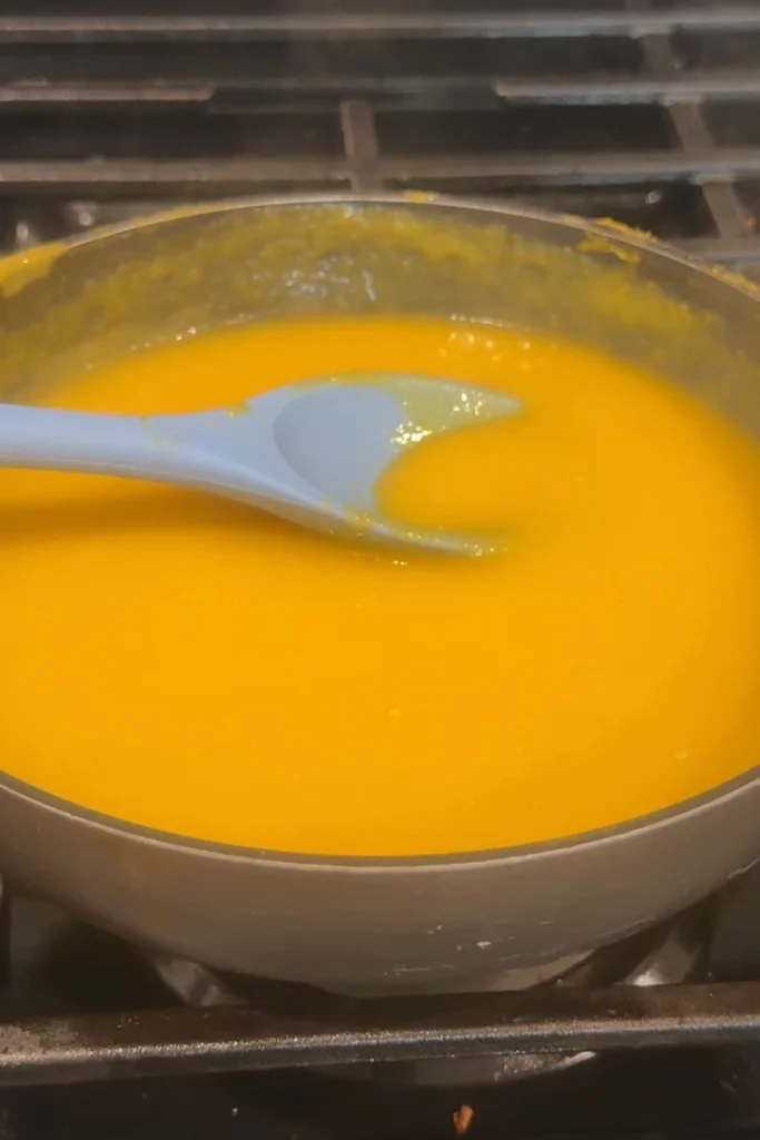 Mango habanero sauce simmering in a saucepan on the stove.
