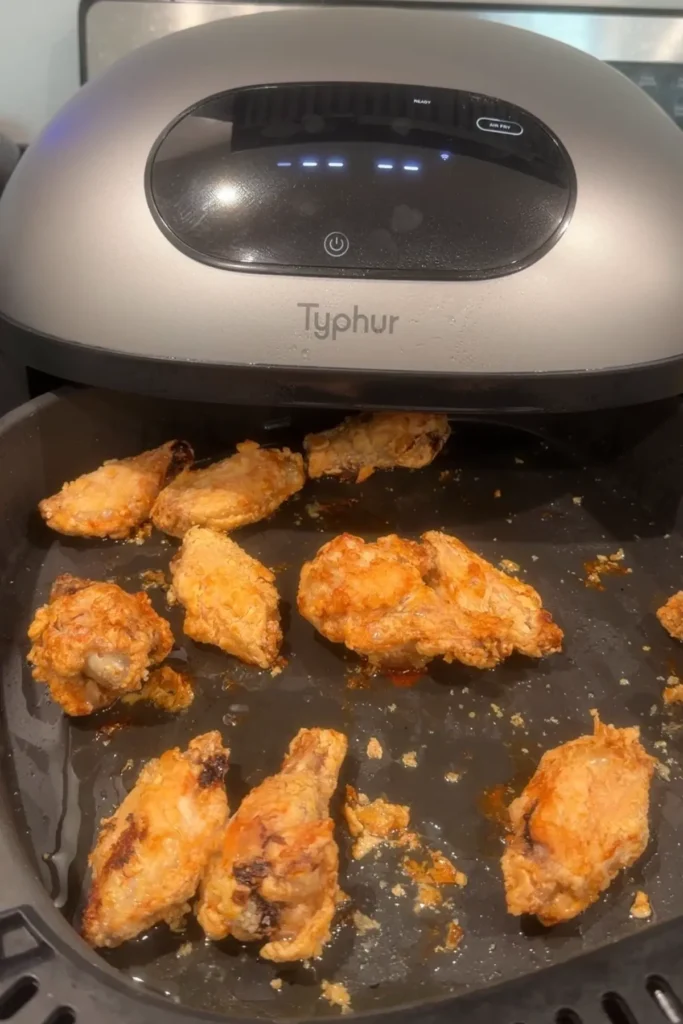 Crispy air fryer chicken wings cooking in the air fryer basket.