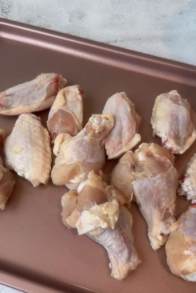 Raw chicken wings arranged on a baking sheet before seasoning.