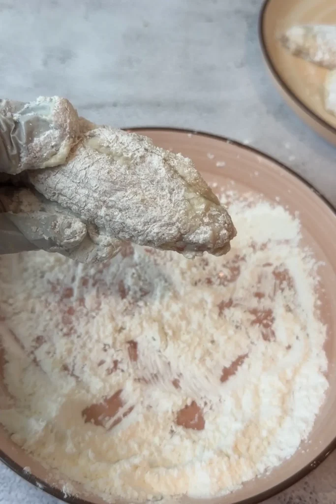 Chicken wing dredged in cornstarch mixture for a crispy air fryer coating.