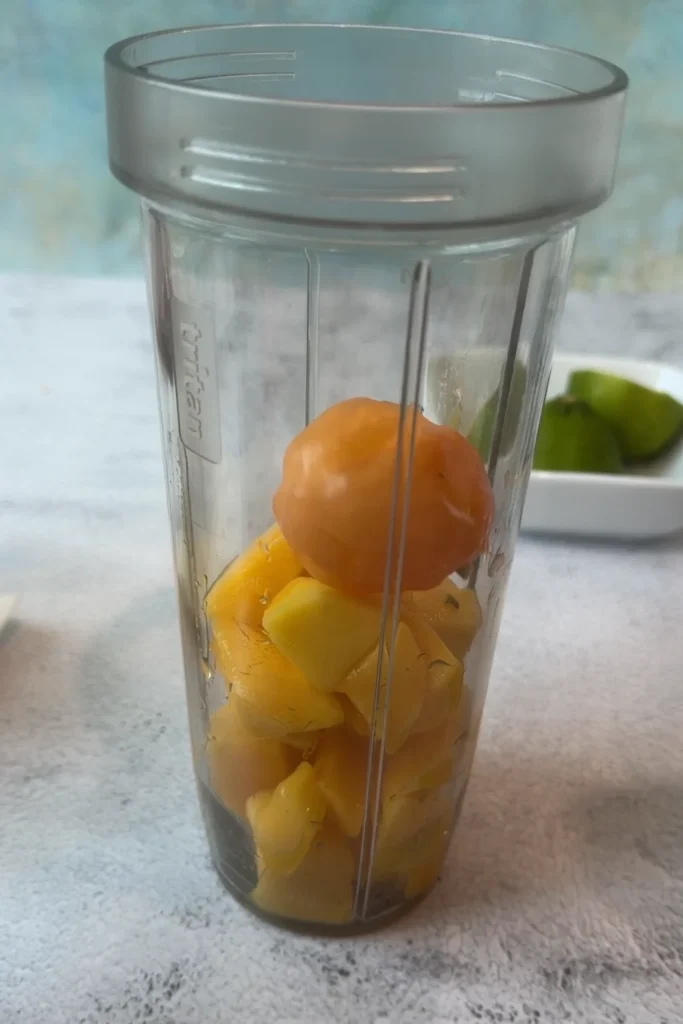 Mango chunks and a habanero pepper in a blender cup for homemade mango habanero sauce.
