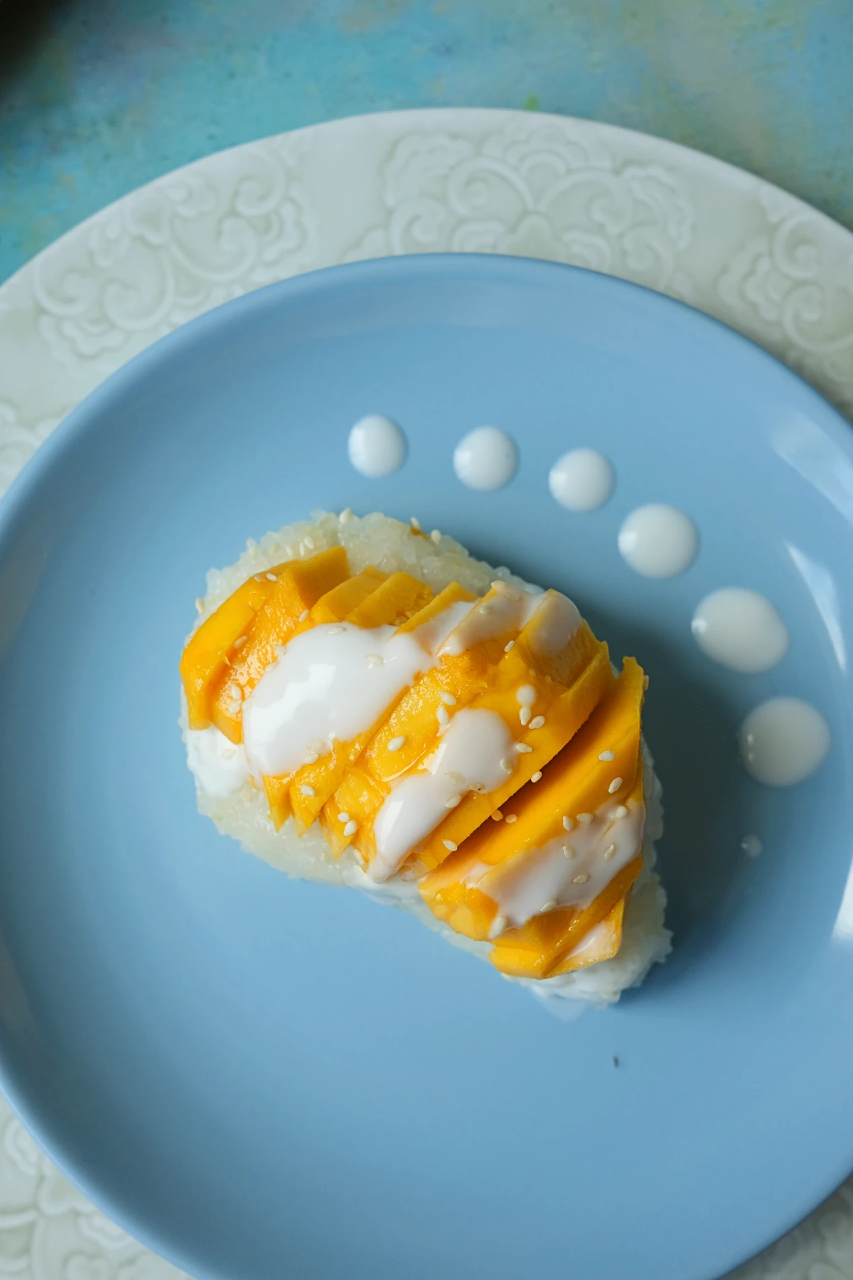 Overhead view of Thai mango sticky rice with ripe mango slices, coconut drizzle, and sesame seed garnish.