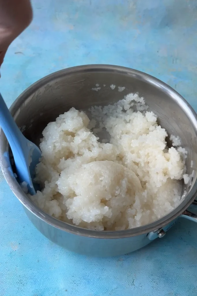 Mixing steamed glutinous rice into the coconut milk mixture until creamy and evenly coated.