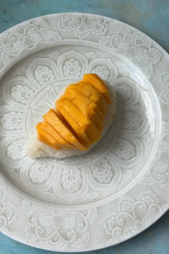 Fresh mango slices arranged over a mound of cooked sticky rice before adding coconut sauce.