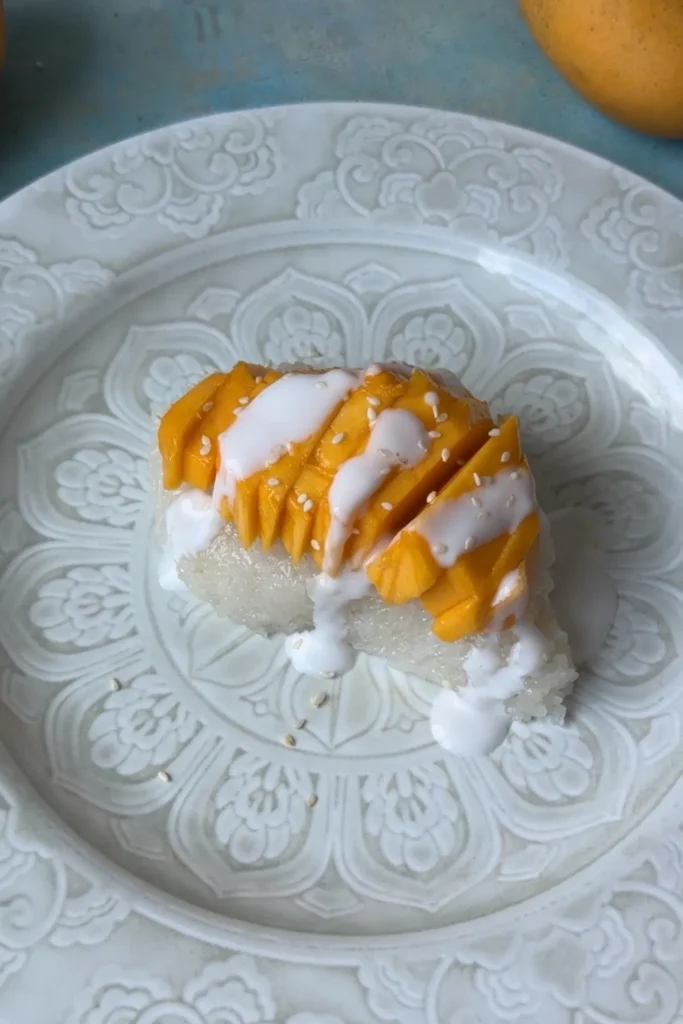 Mango sticky rice topped with coconut sauce and sprinkled with sesame seeds.