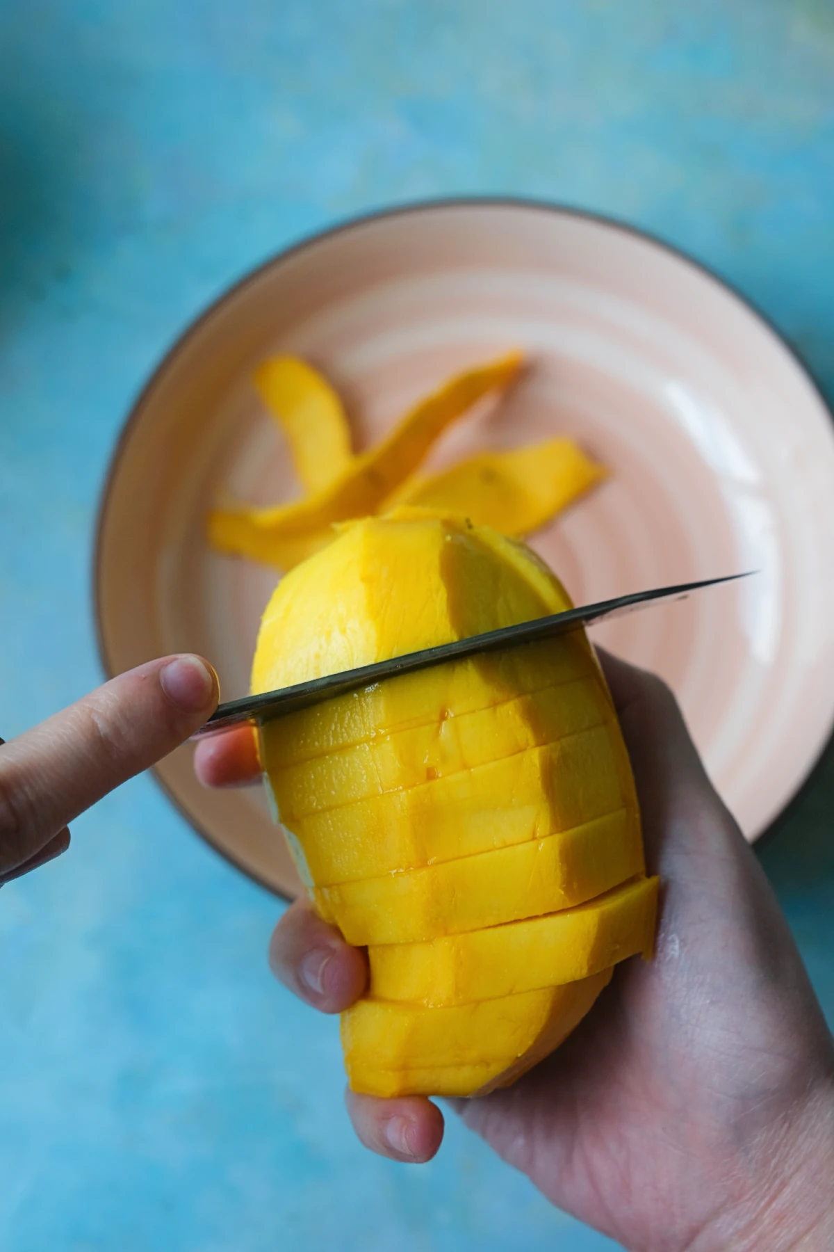 Slicing a ripe Manila mango into thin pieces for serving with sticky rice.