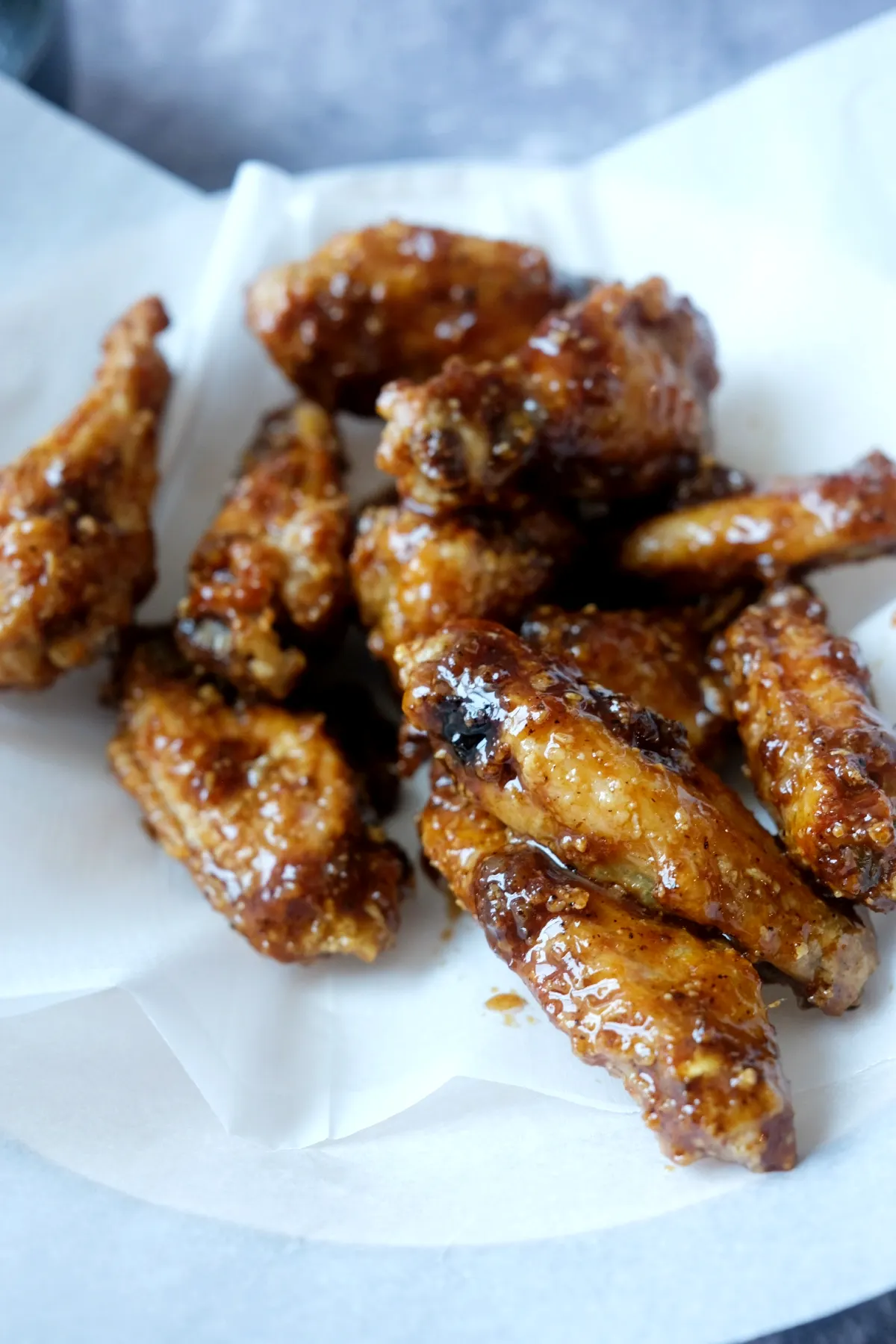 Crispy air fryer soy garlic chicken wings coated in glossy Korean-style garlic sauce on parchment paper.