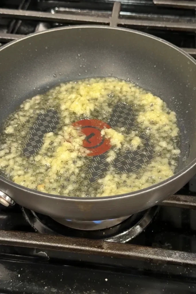 Minced garlic sizzling in oil in a skillet for soy garlic wing sauce.