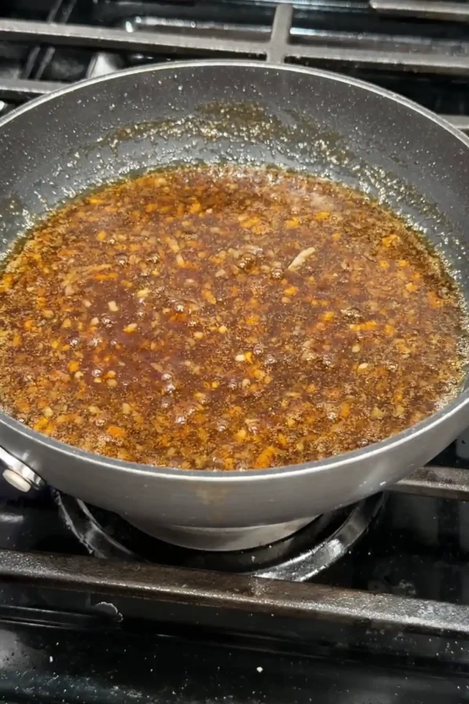 Korean-style soy garlic sauce simmering in a skillet until glossy and thickened.