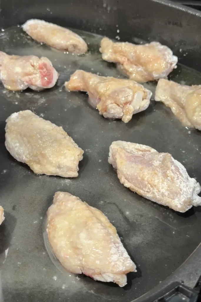 Cornstarch-coated chicken wings arranged in an air fryer basket before cooking.