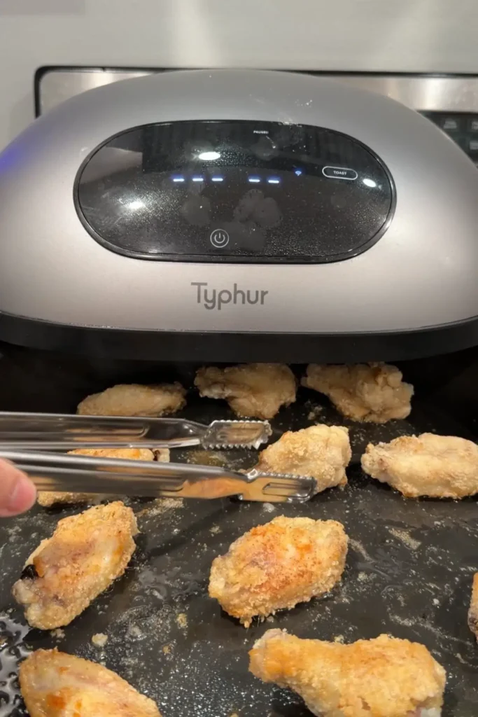 Crispy air fryer chicken wings flipping halfway through cooking in the air fryer.