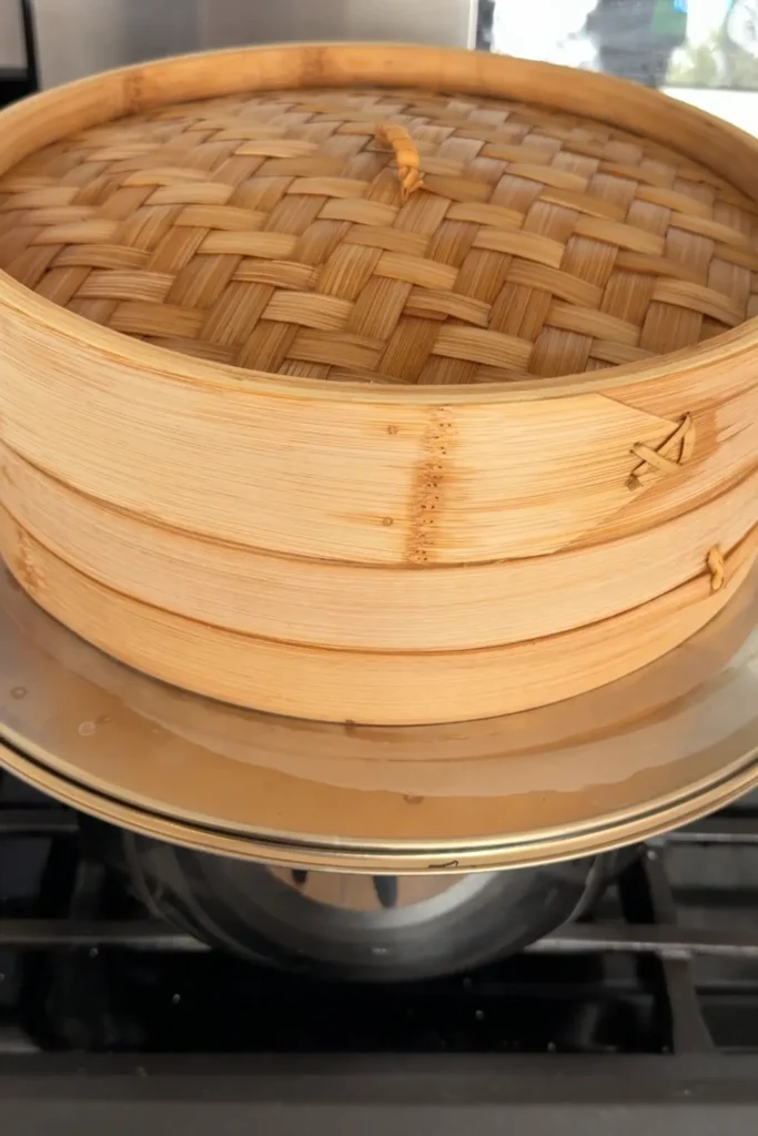 Bamboo steamer set over simmering water for steaming glutinous rice.