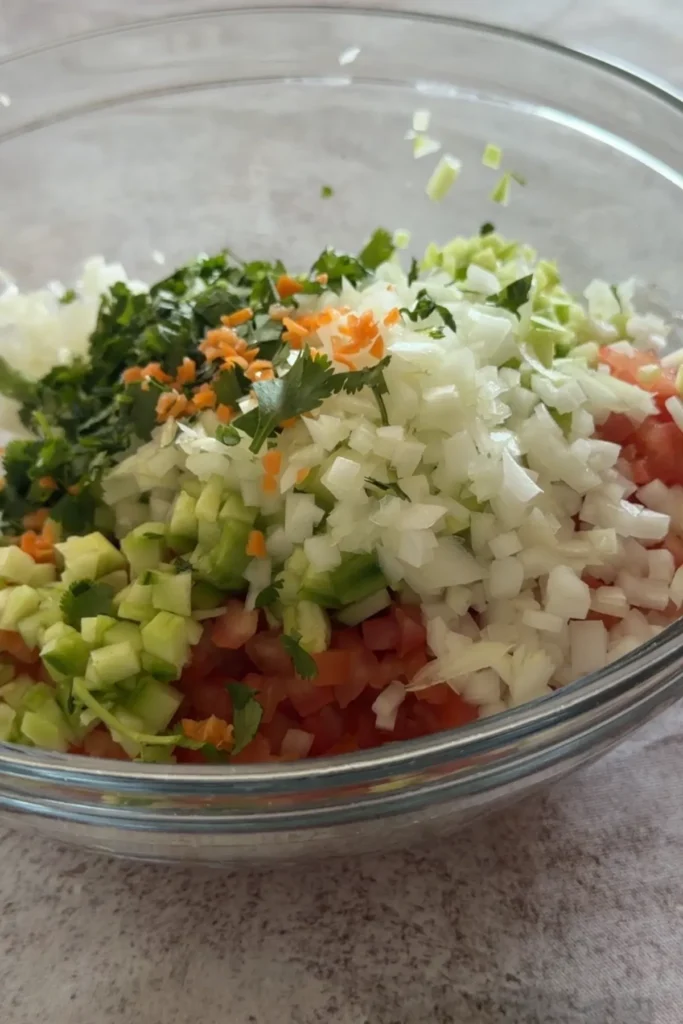 Bowl of diced tomatoes, cucumber, onion, and cilantro before mixing into salsa.