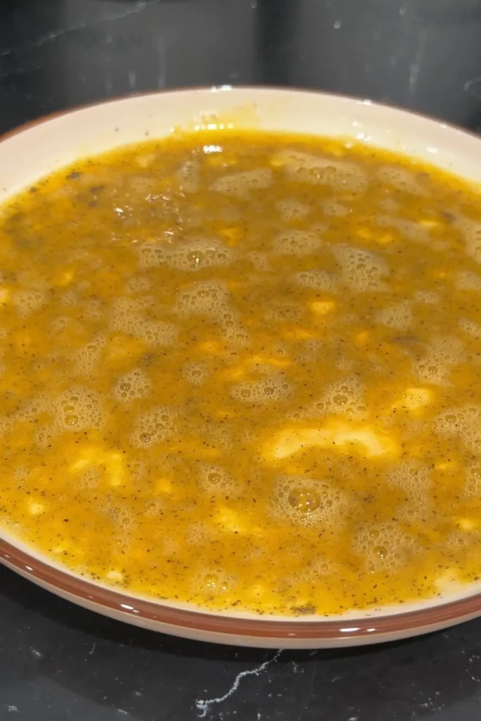 Beaten eggs mixed with salt and black pepper in a shallow bowl before adding the eggplant.