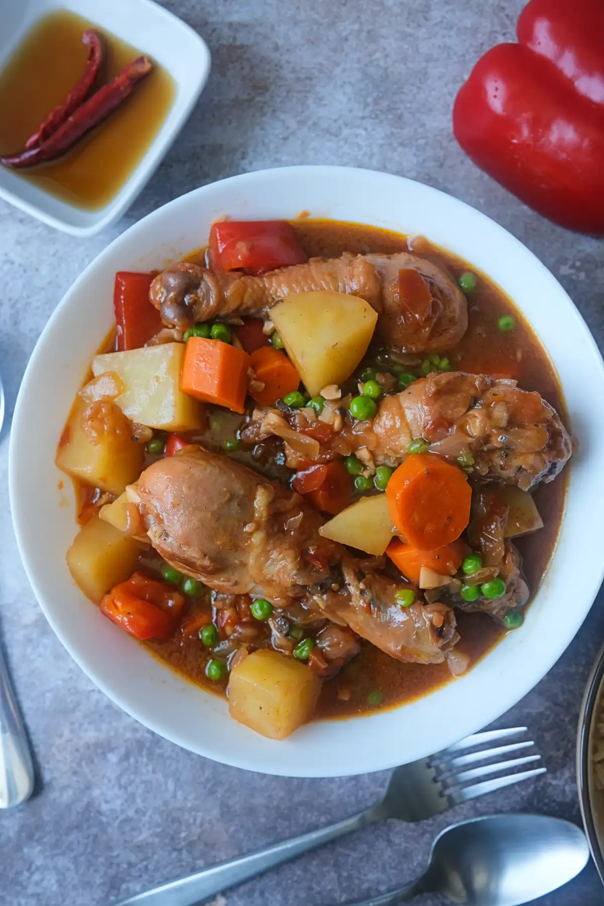 Chicken Afritada served in a bowl with tender chicken, potatoes, carrots, bell peppers, and green peas in a rich tomato sauce