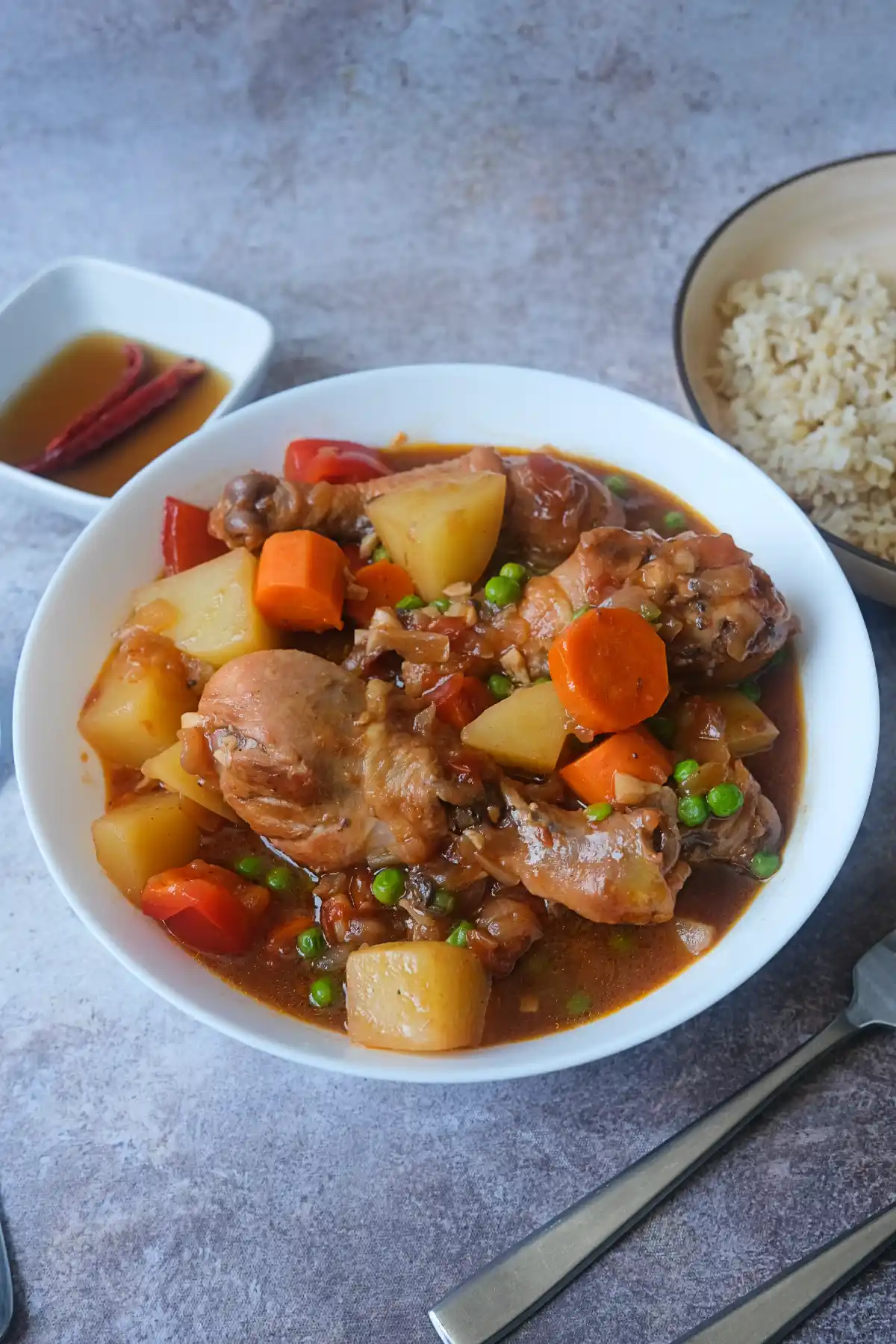 Homemade Chicken Afritada with potatoes, carrots, bell peppers, and green peas in a flavorful tomato-based stew