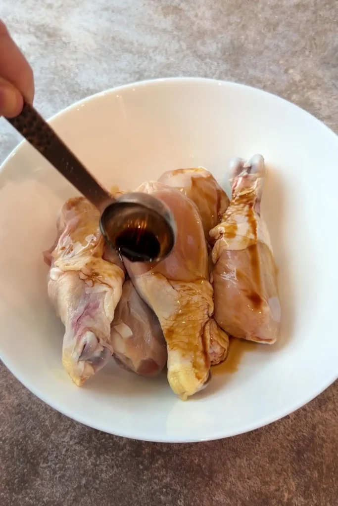 Chicken drumsticks marinating in soy sauce and calamansi for homemade Filipino chicken afritada