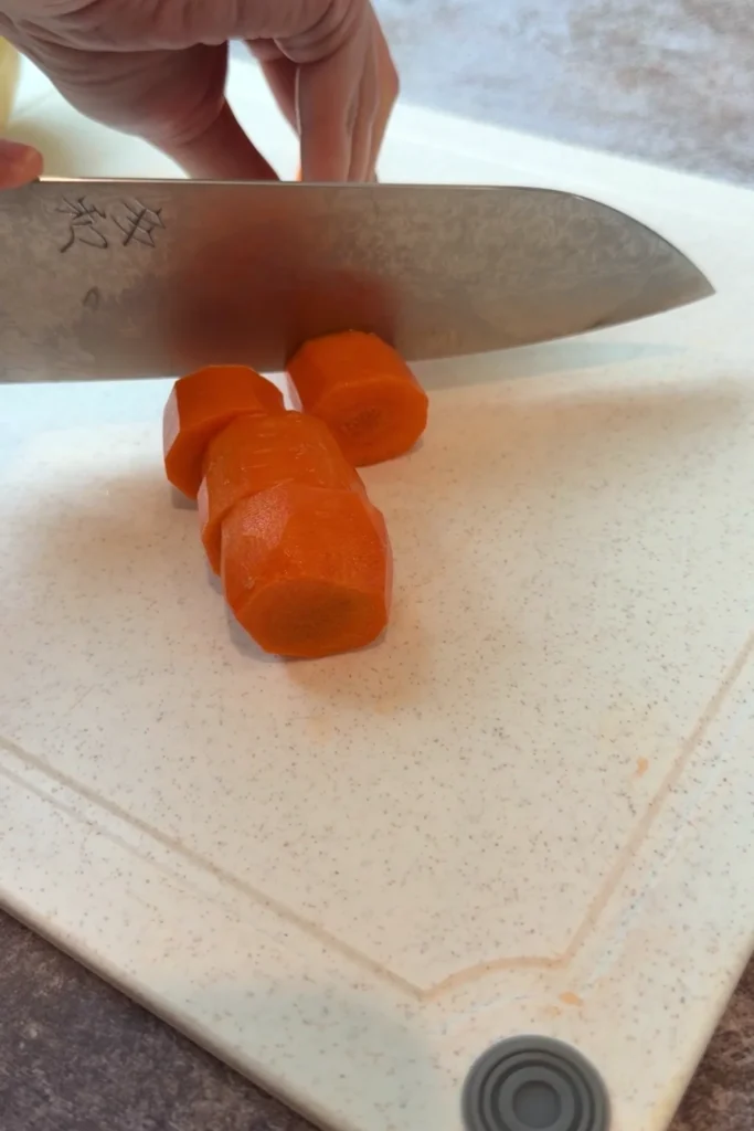 Slicing a carrot into chunks for classic Filipino chicken afritada recipe