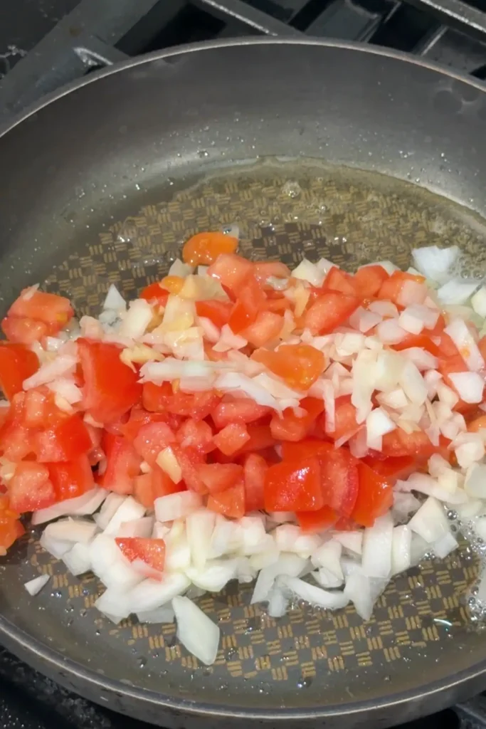 Diced tomatoes, onions, and garlic sautéing in oil for chicken afritada sauce