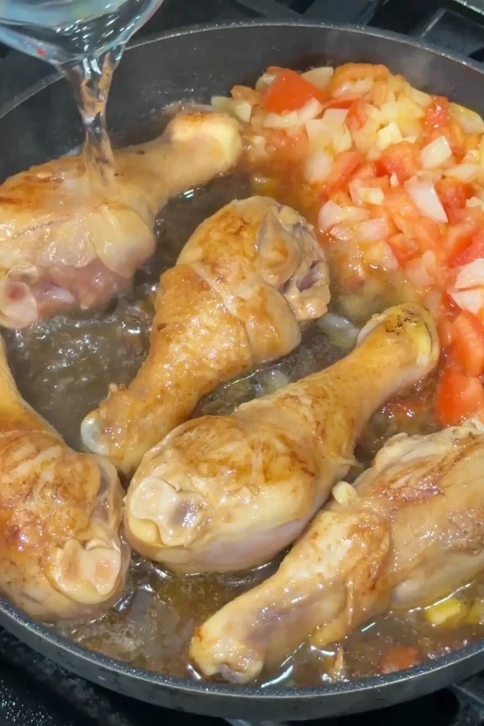 Adding water to the pan to create the base for Filipino chicken afritada