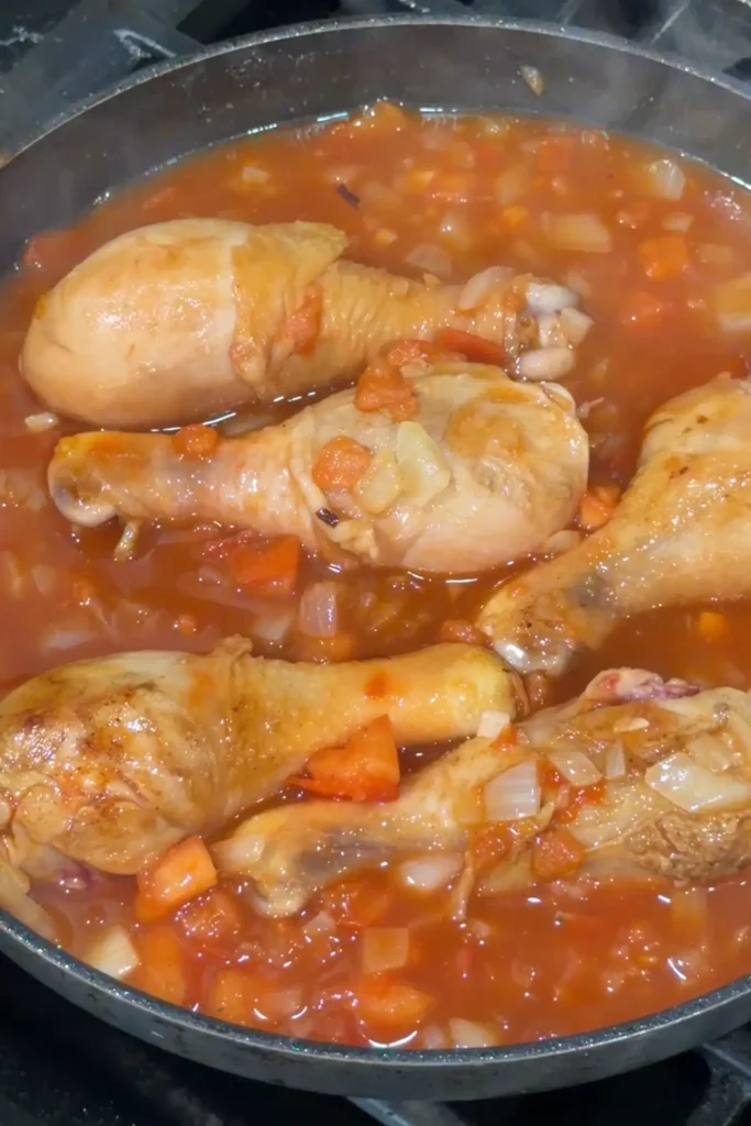 Chicken simmering in a savory tomato-based sauce for traditional Filipino afritada
