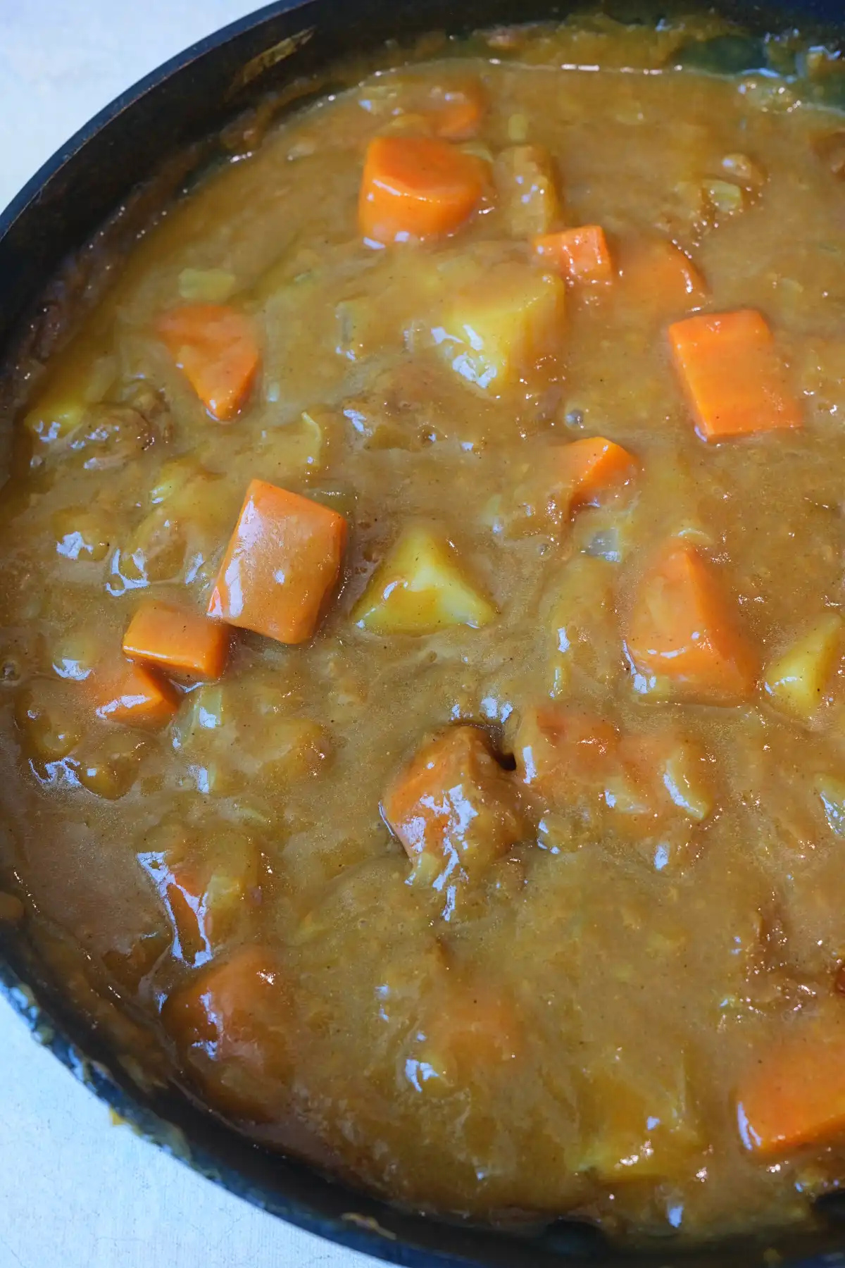 Close-up of homemade Japanese curry with tender potatoes, carrots, and onions in a thick, rich curry sauce.