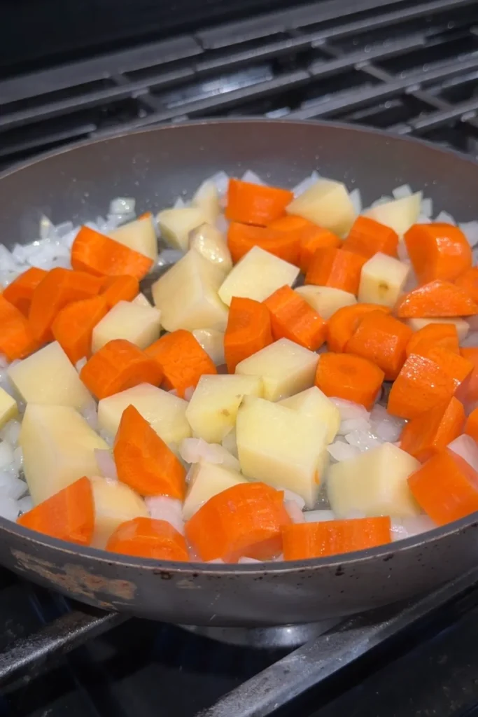 Chopped carrots and potatoes cooking with onions for Japanese curry.