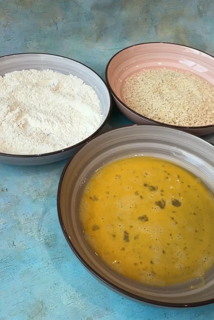 Three breading stations with seasoned flour, beaten eggs, and panko breadcrumbs.
