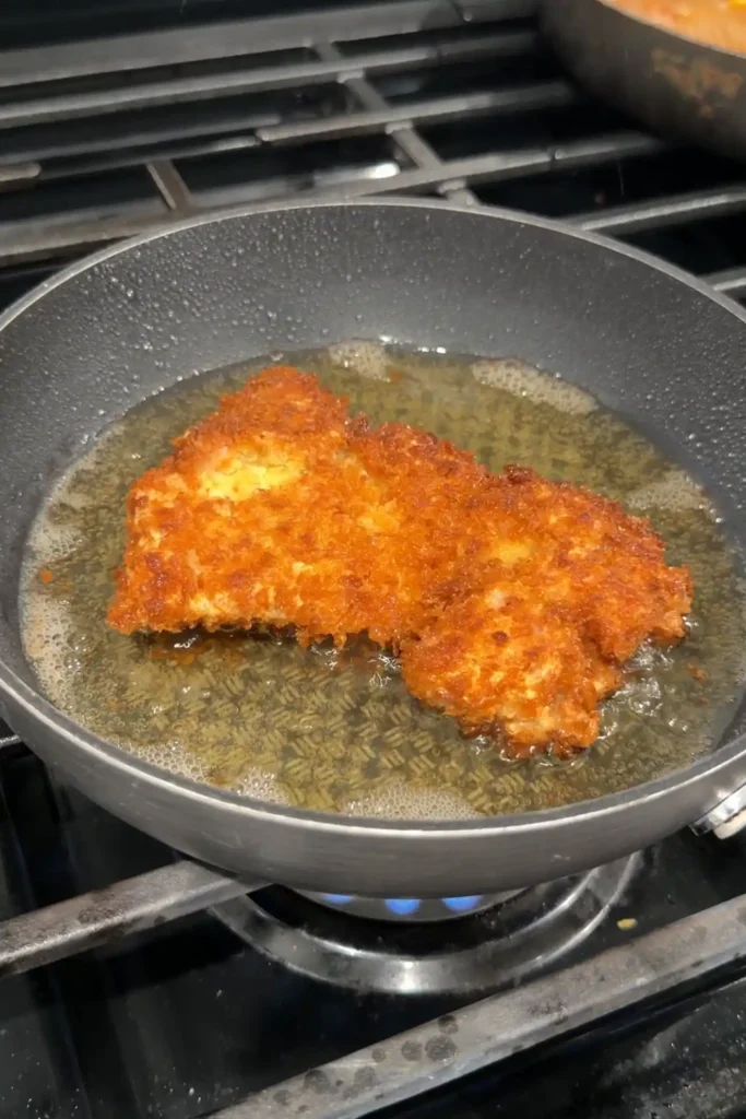 Golden brown chicken katsu frying in a skillet for Japanese katsu curry.