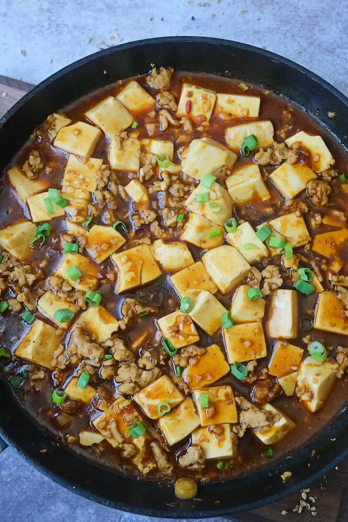 Close-up of chicken mapo tofu featuring soft tofu cubes in a rich doubanjiang sauce.