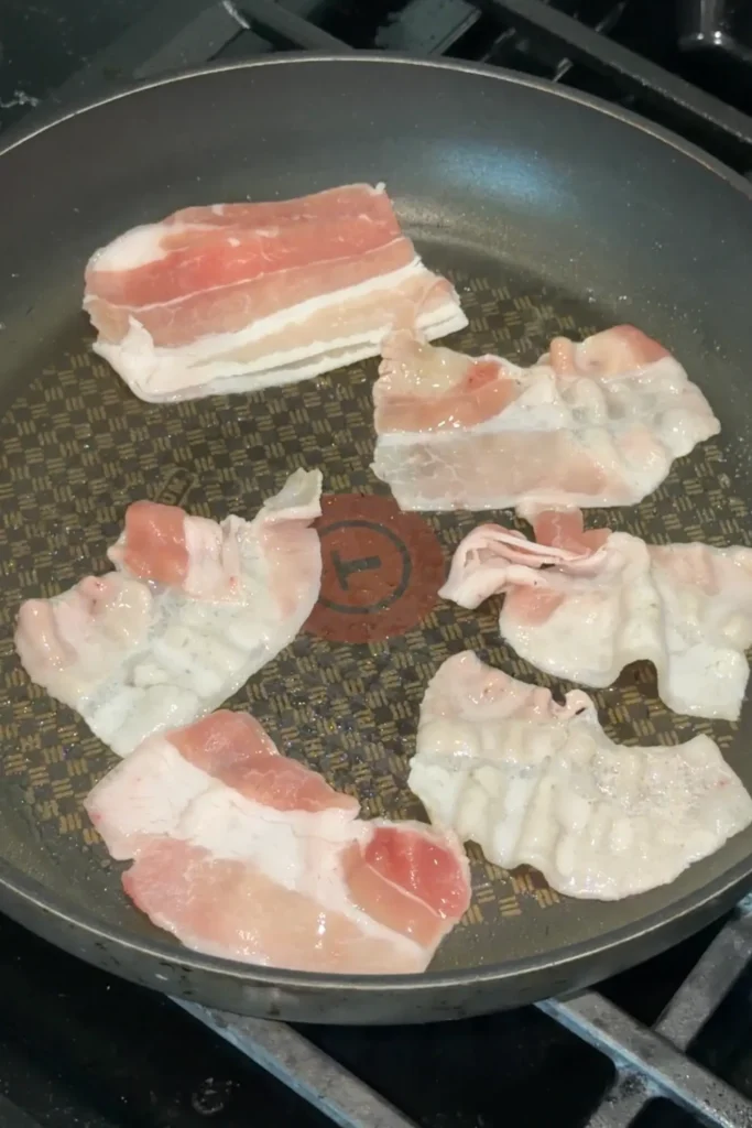 Thinly sliced pork belly cooking in a skillet for Japanese Curry Udon