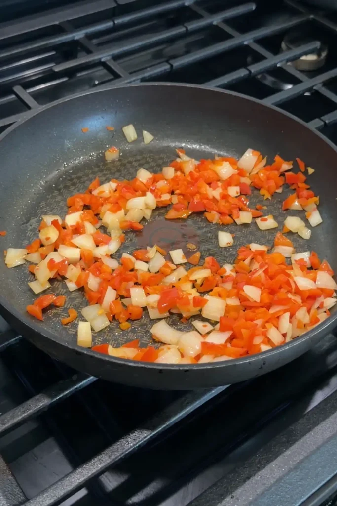 Diced onions and bell peppers sautéing in a skillet for cheesy ground beef quesadillas.
