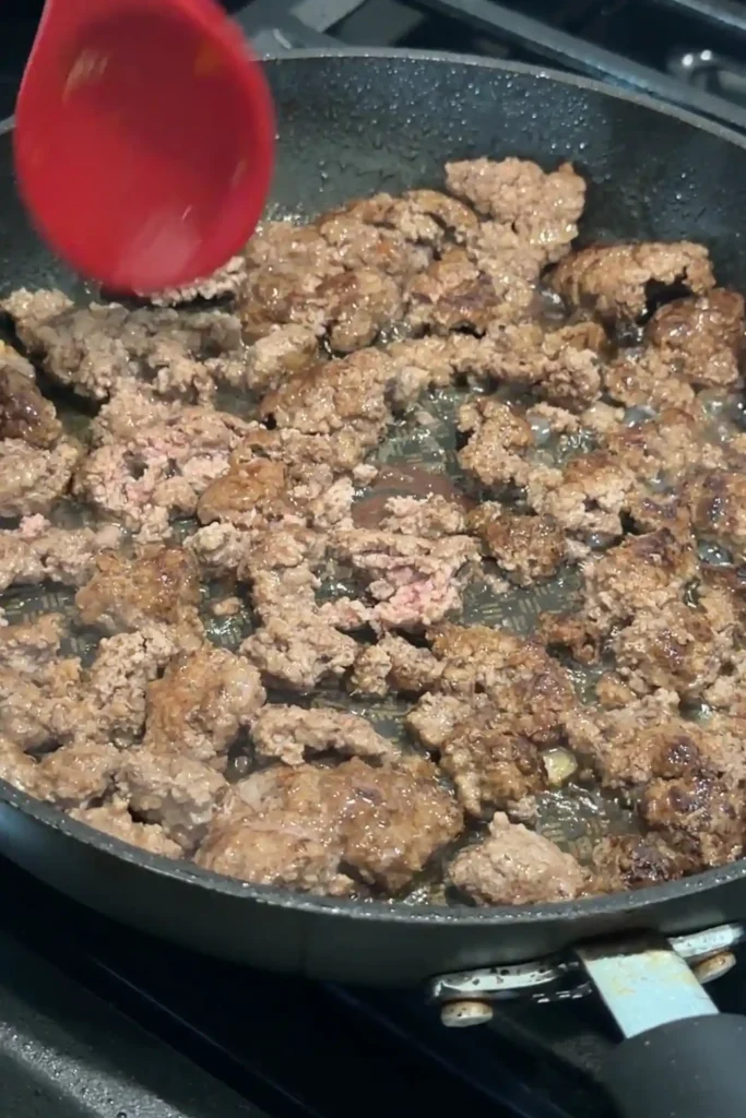 Browned ground beef cooking in a skillet.