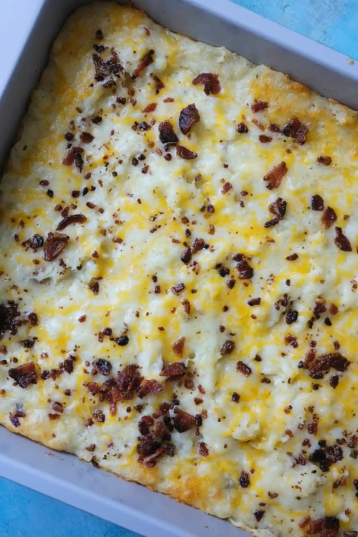 Overhead view of loaded baked potato casserole topped with melted cheese and bacon.