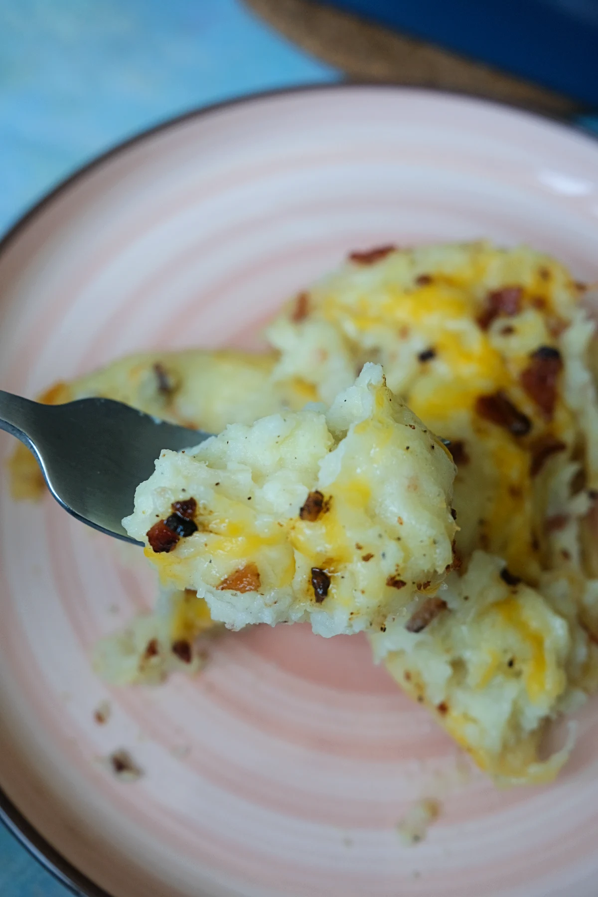 Fork holding a bite of cheesy loaded baked potato casserole.