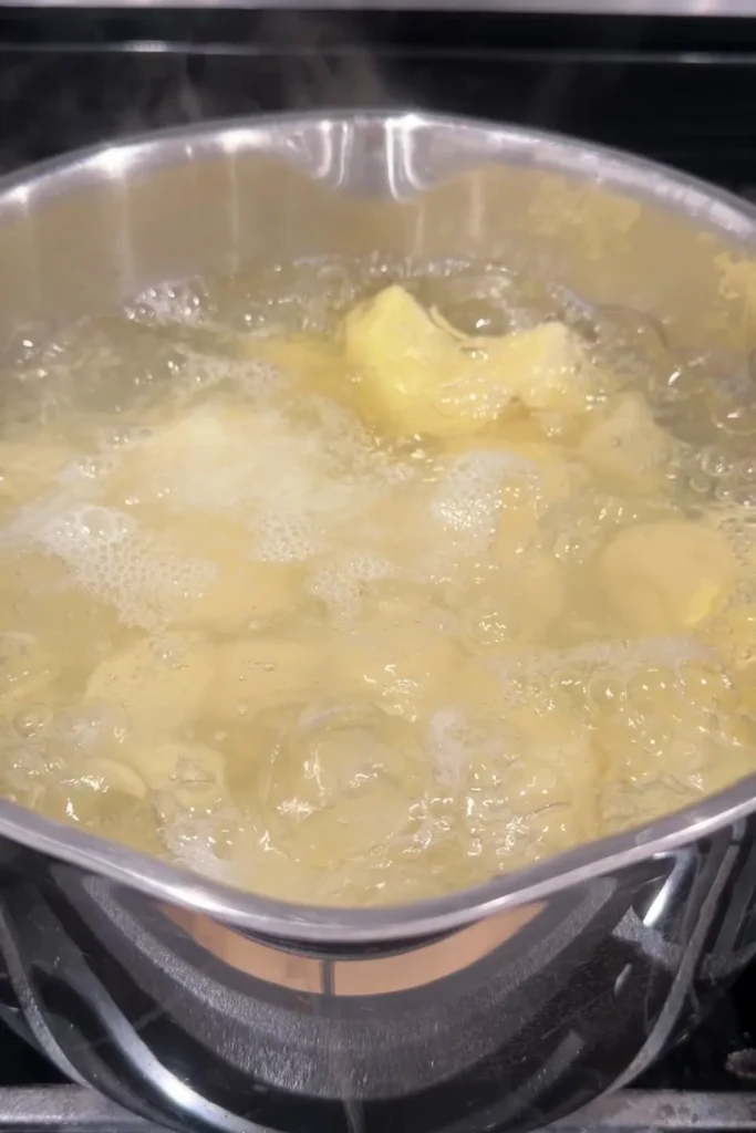 Diced potatoes boiling in a pot of water on the stovetop.
