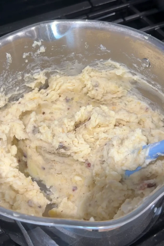 Creamy loaded baked potato mixture mixed with cheese and bacon in a pot.