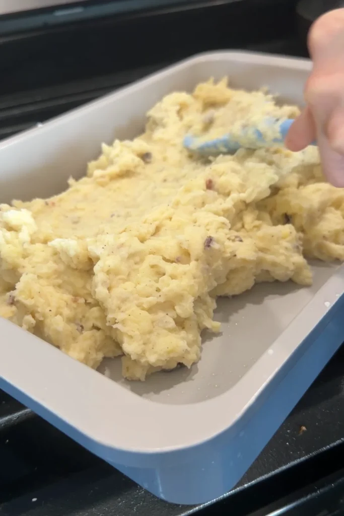 Creamy mashed potato mixture spread into a greased baking dish.