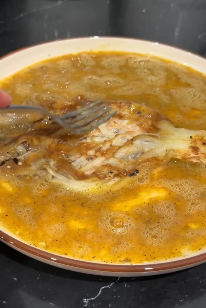 Peeled roasted eggplant being mashed into the beaten egg mixture with a fork.