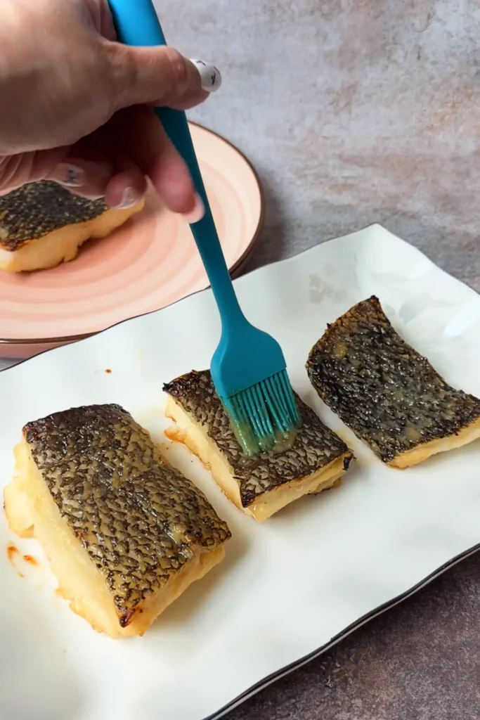 Brushing boiled miso glaze over cooked Chilean sea bass