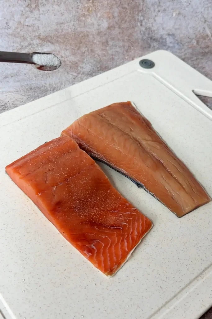 Salmon fillets seasoned with salt on a cutting board before cooking for salmon onigiri