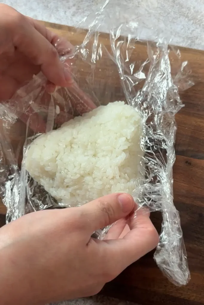 Triangle-shaped salmon onigiri placed on a sheet of nori for wrapping