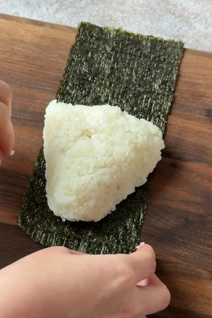 Wrapping a salmon onigiri with nori to create a classic Japanese rice ball