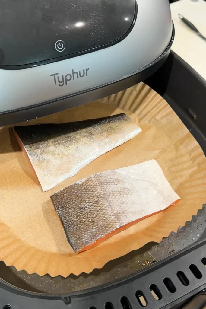 Salmon fillets cooking in an air fryer basket for homemade salmon onigiri filling