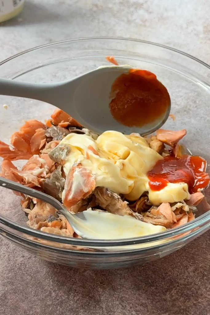 Flaked cooked salmon in a bowl before mixing with mayonnaise and seasonings for onigiri filling