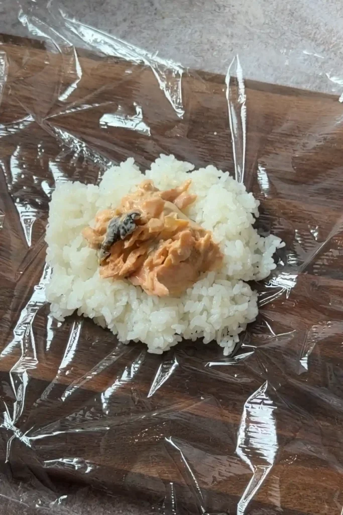 Creamy salmon filling placed in the center of rice before shaping an onigiri